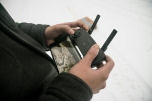 Close-up of hands using a drone controller with a smartphone attached outdoors.