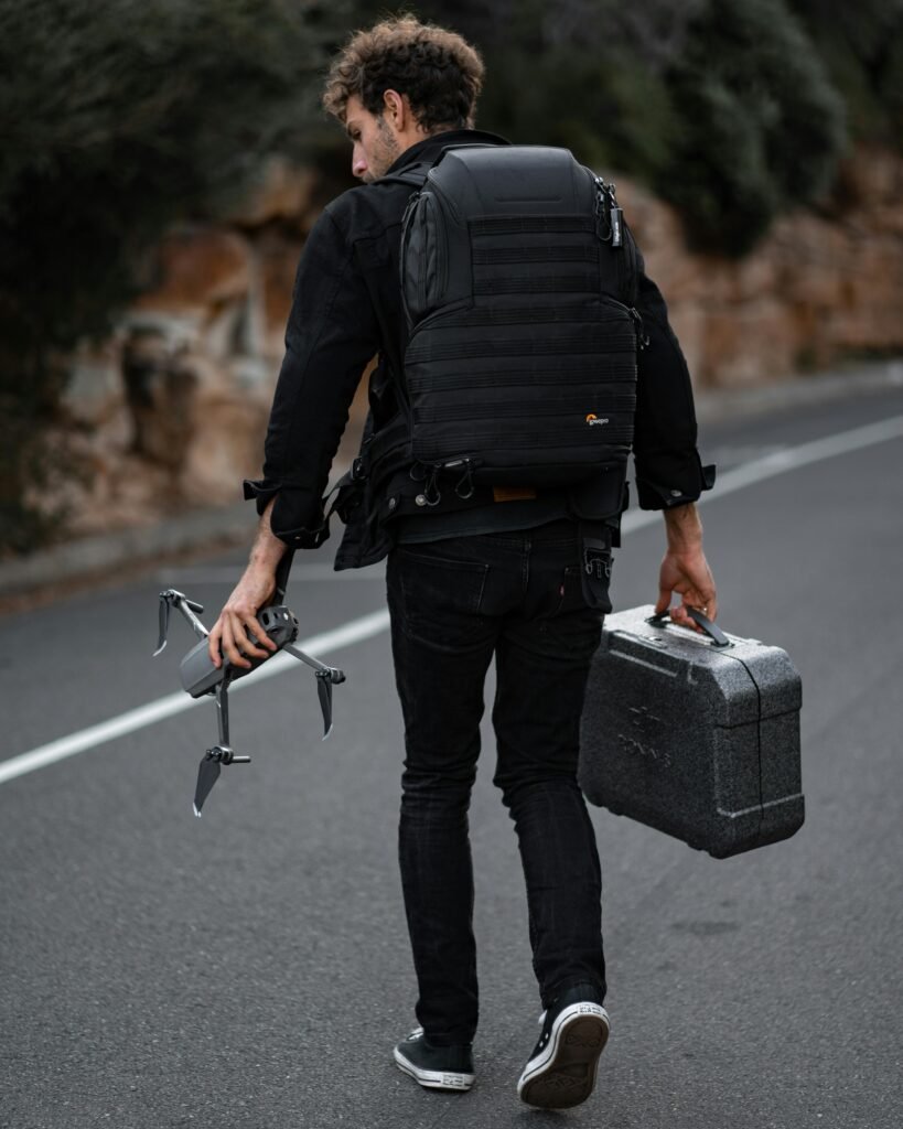 A man carrying a drone and backpack walks on a road near Bondi Beach, Australia.